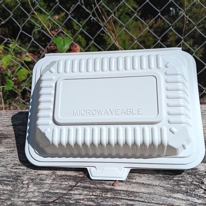 White microwaveable container on a wooden surface with a chain-link fence in the background