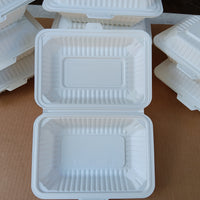 Stack of white foam food containers with lids on a brown surface